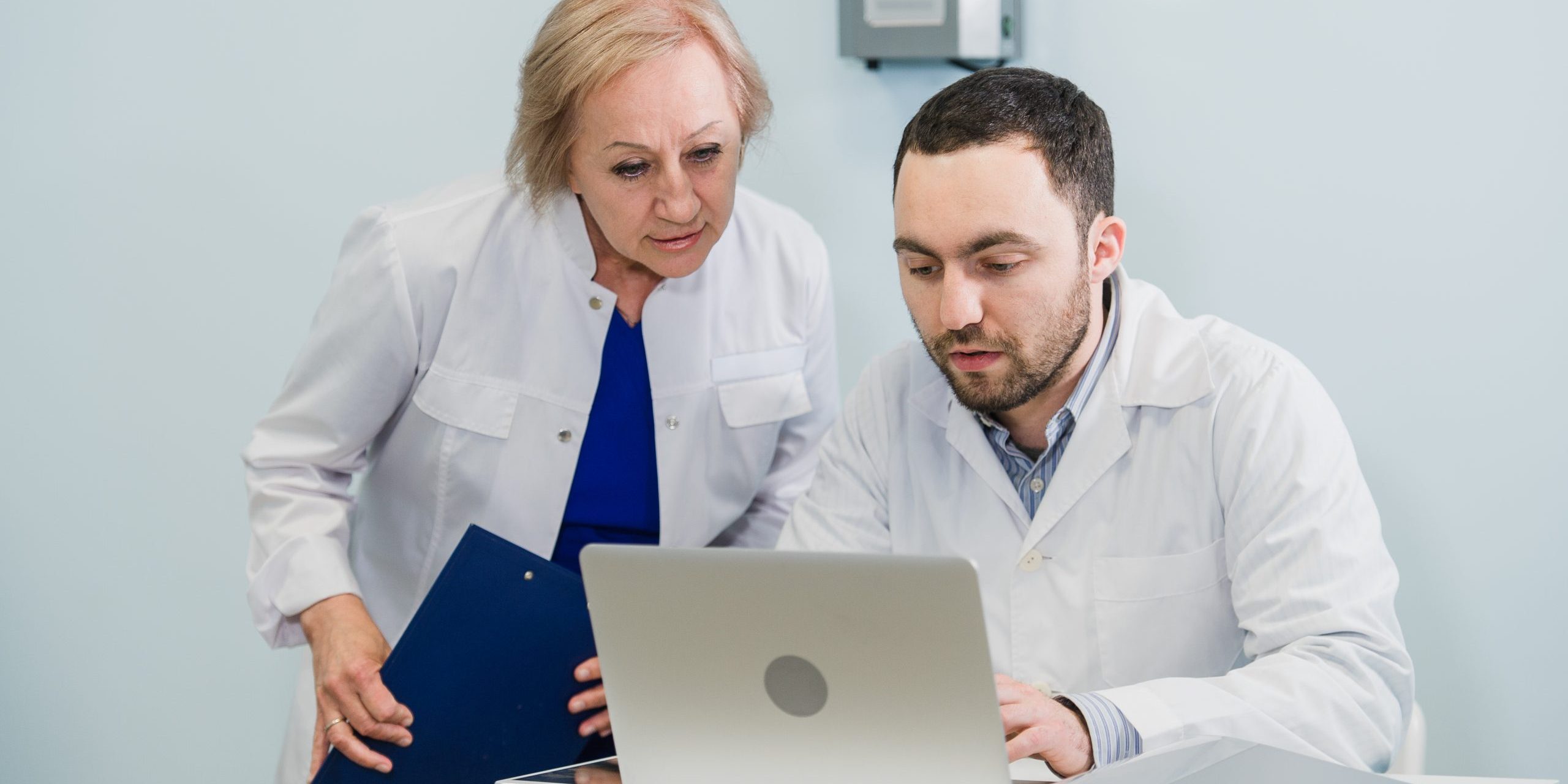 Doctor and nurse reviewing patient information on a laptop computer in an office setting